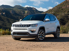 A white Jeep Compass sitting near the mountains