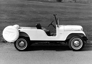 A black & white, sideview image of a 1957 Jeep CJ-6 on the road